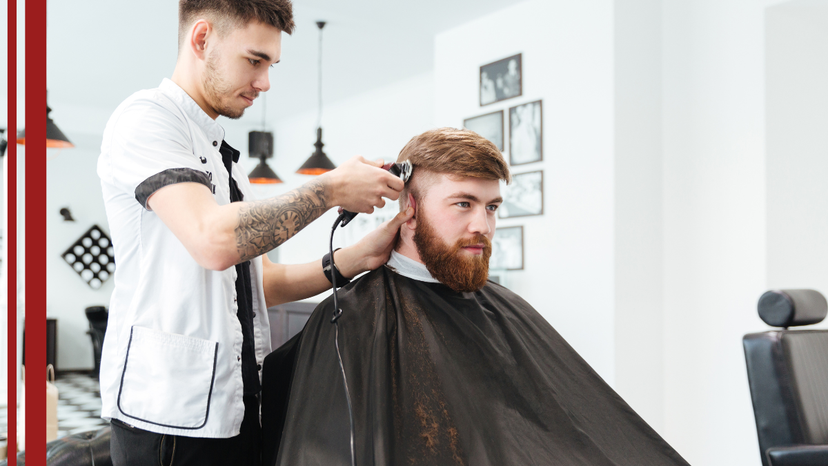 A client sits in a barbers chair as they discuss his new hair cut and hair maintenance.