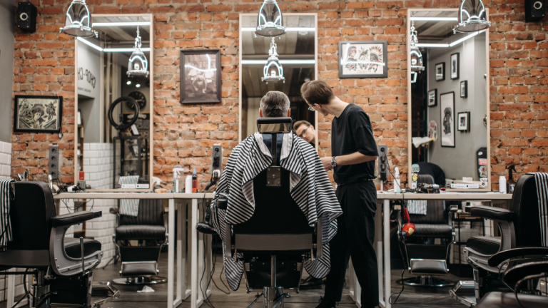 A client sits in a barber chair, awaiting his barbershop father's day promo cut.