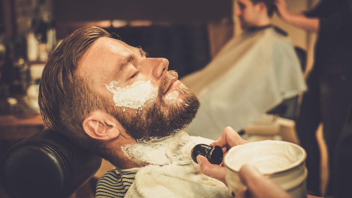 A client lets his barber put cream on his face before he gets to his secret beard trimming tips.